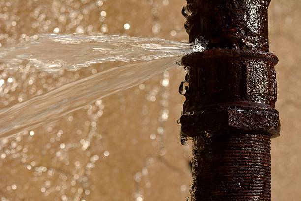 Detailed view of industrial steel pipes and a gas meter on a brick wall.